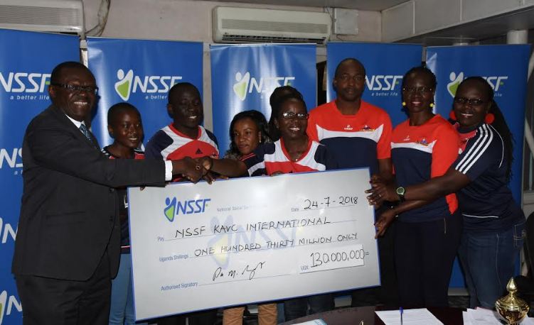 NSSF Deputy Managing Director Patrick Ayola hands over a dummy cheque to KAVC's Technical Director Shillah Buyundo at Workers House. 