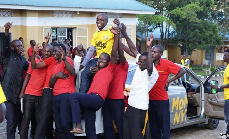 Dickens Muhereza, a bursar at Alliance Secondary School Ibanda celebrates with the school's students.